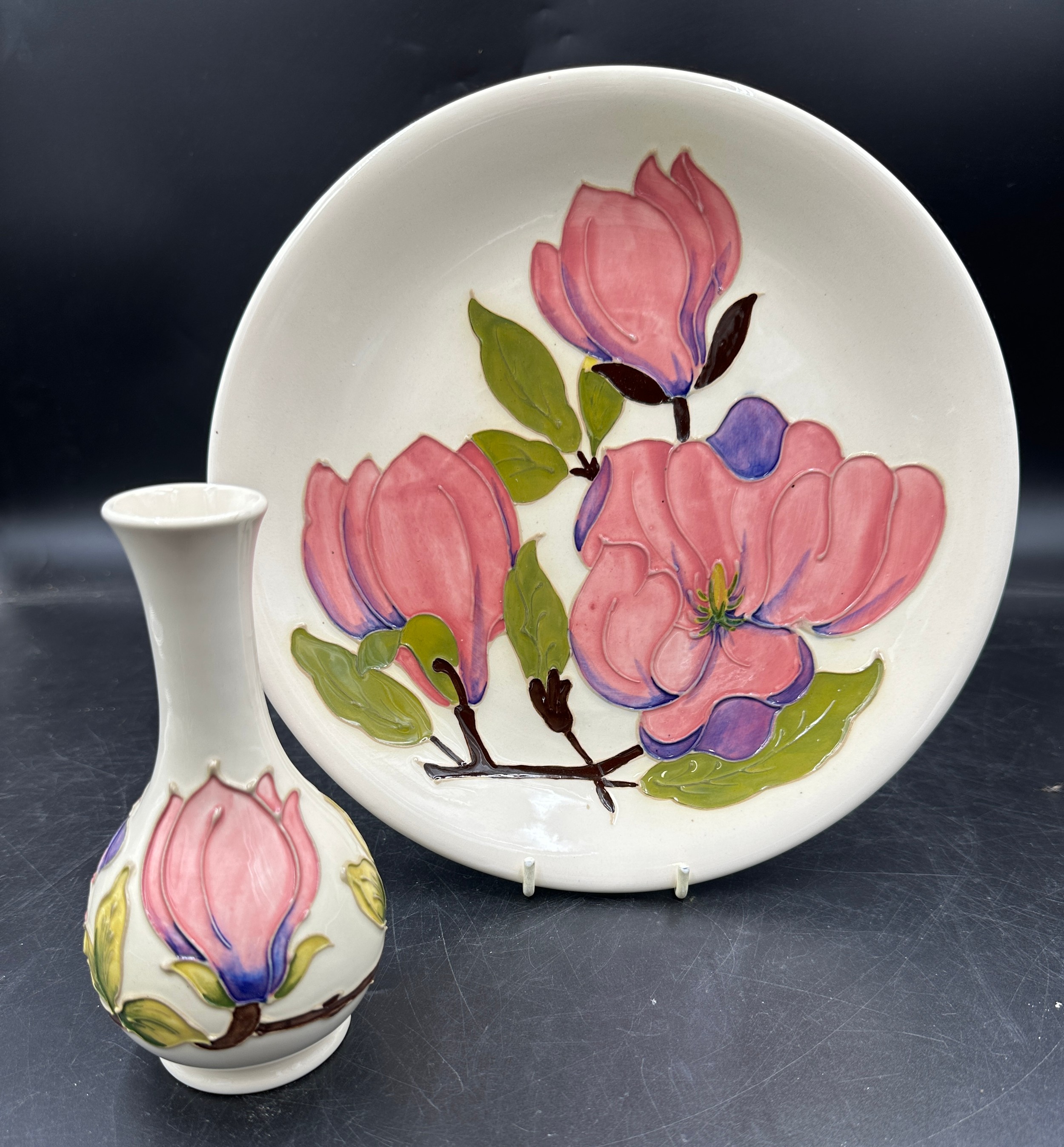 Two Moorcroft ceramics in the Magnolia pattern, a plate approx 26cm d and a bud vase approx 15.5cm