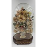 A glass display dome containing a vintage floral display in continental ceramic vase on an inlaid