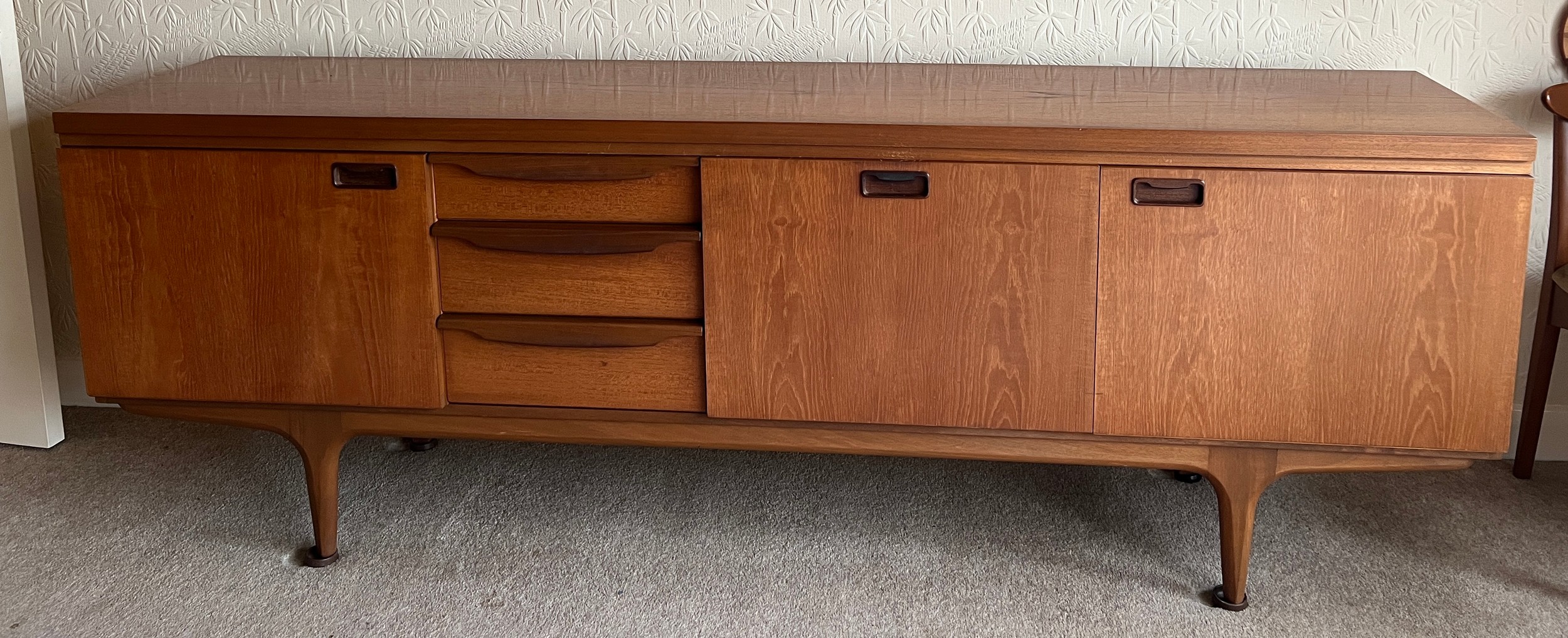 A mid 20thC teak sideboard with three cupboards and three drawers 220cm l x 45cm d x 77cm h.