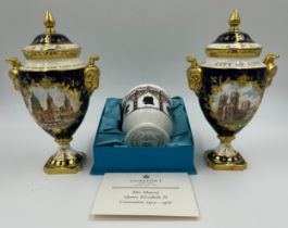 Coalport: Two twin-handled commemorative urn shaped vases with covers and twin goat head handles,
