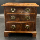 A mahogany miniature chest of three drawers on bracket feet. 30cm h x 31cm w x 19cm d. Marked to