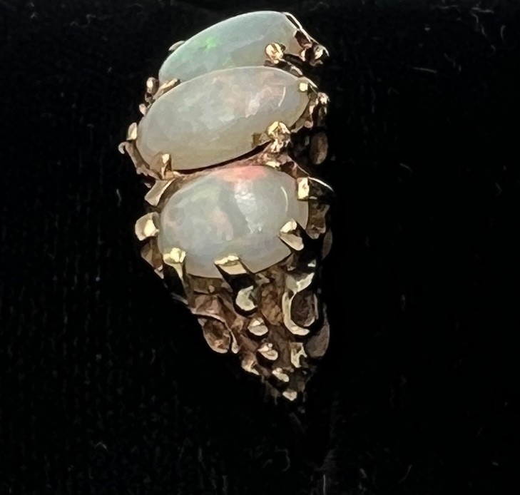 A nine carat gold ring set with three opals. Size J/K. Weight 3.7gm.