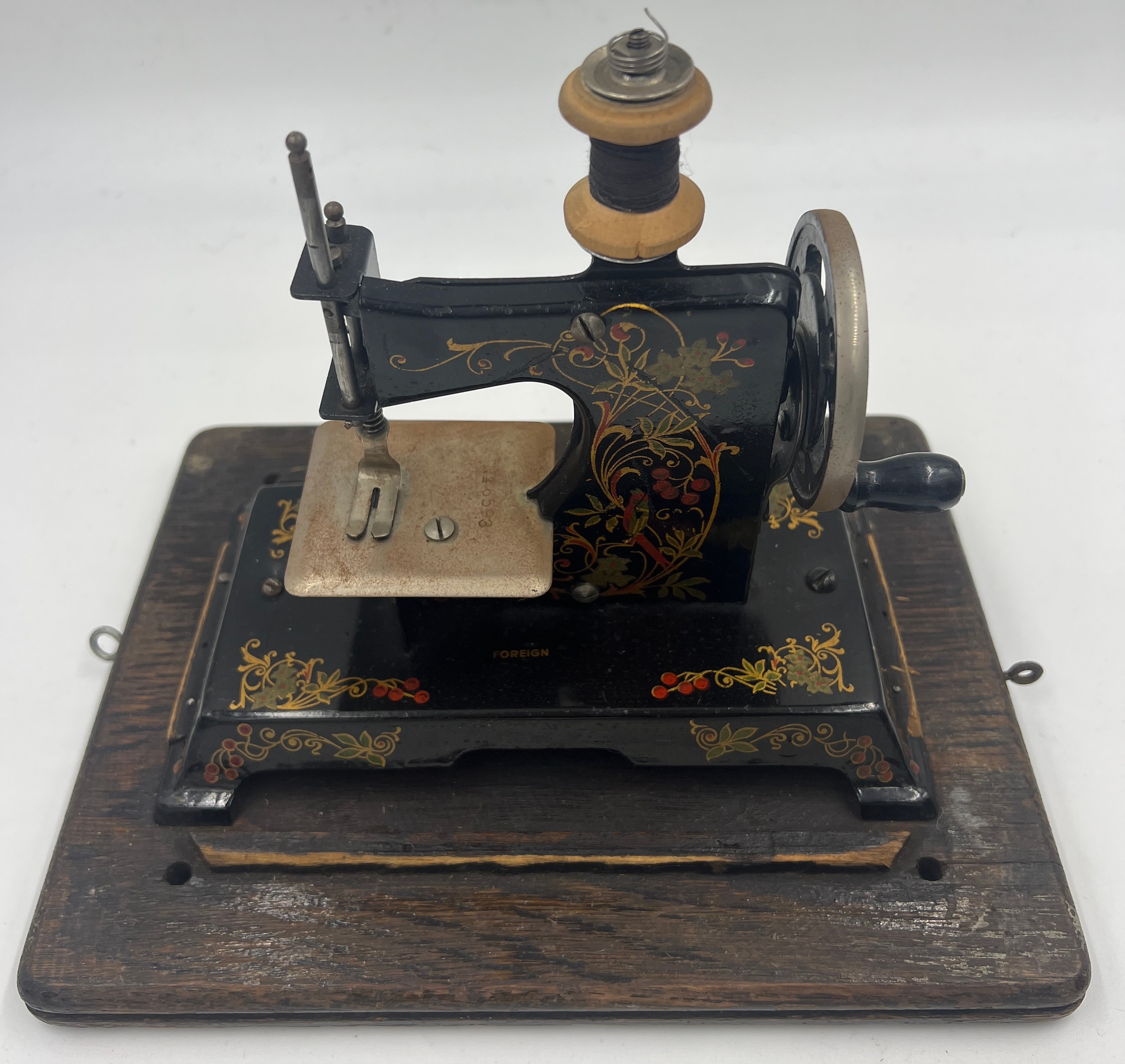 A child’s metal sewing machine in an oak Edison case. 25cm w x 22cm h.