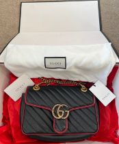A Gucci Marmont black with red trim and gold coloured chain hand bag, together with original box and