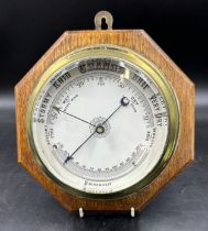 Ships brass cased circular barometer on an octagonal oak plaque. Barometer face 16cm. Plaque 25cm.