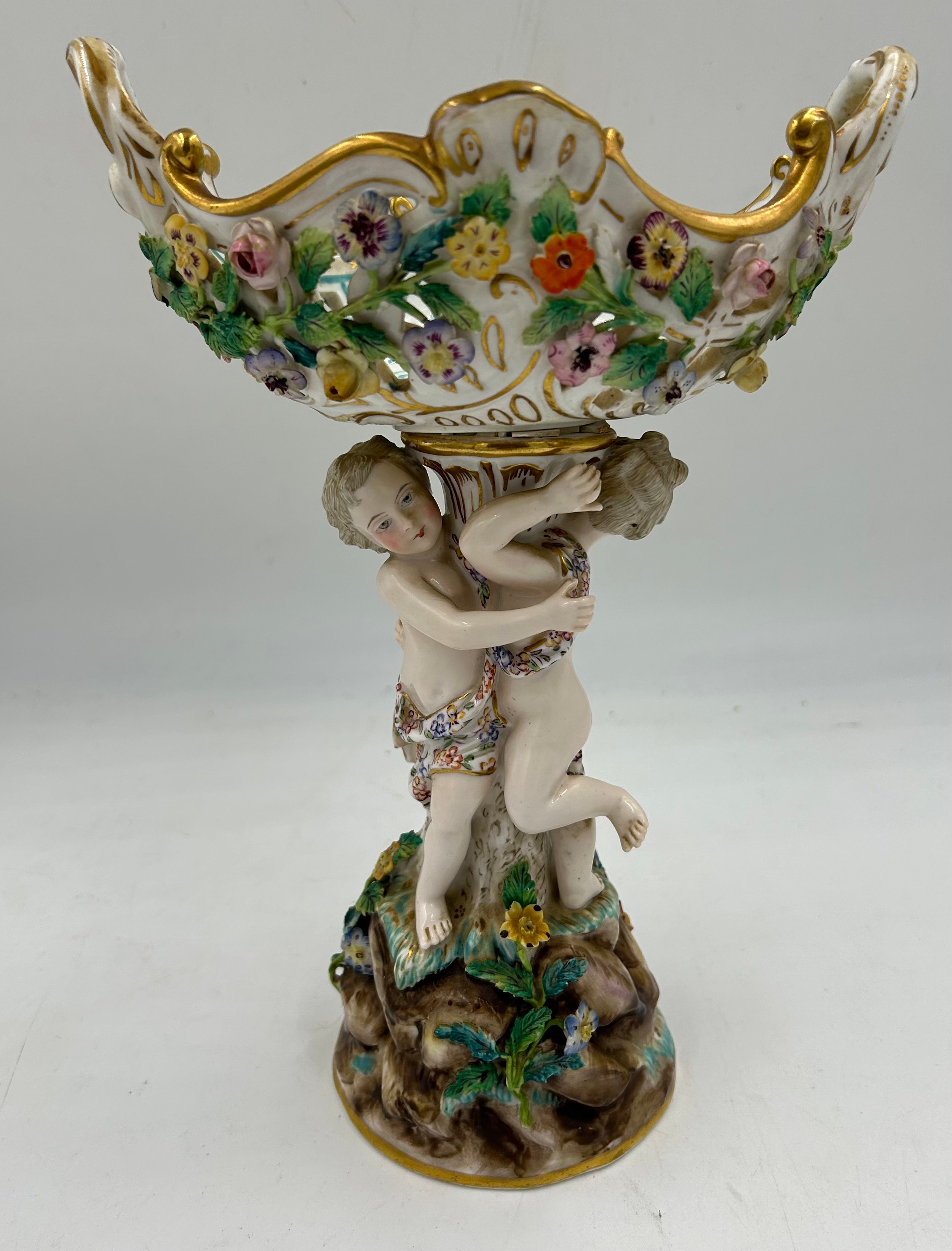 A Meissen table centrepiece with a pierced twin-handled basket, a supporting column with two putti