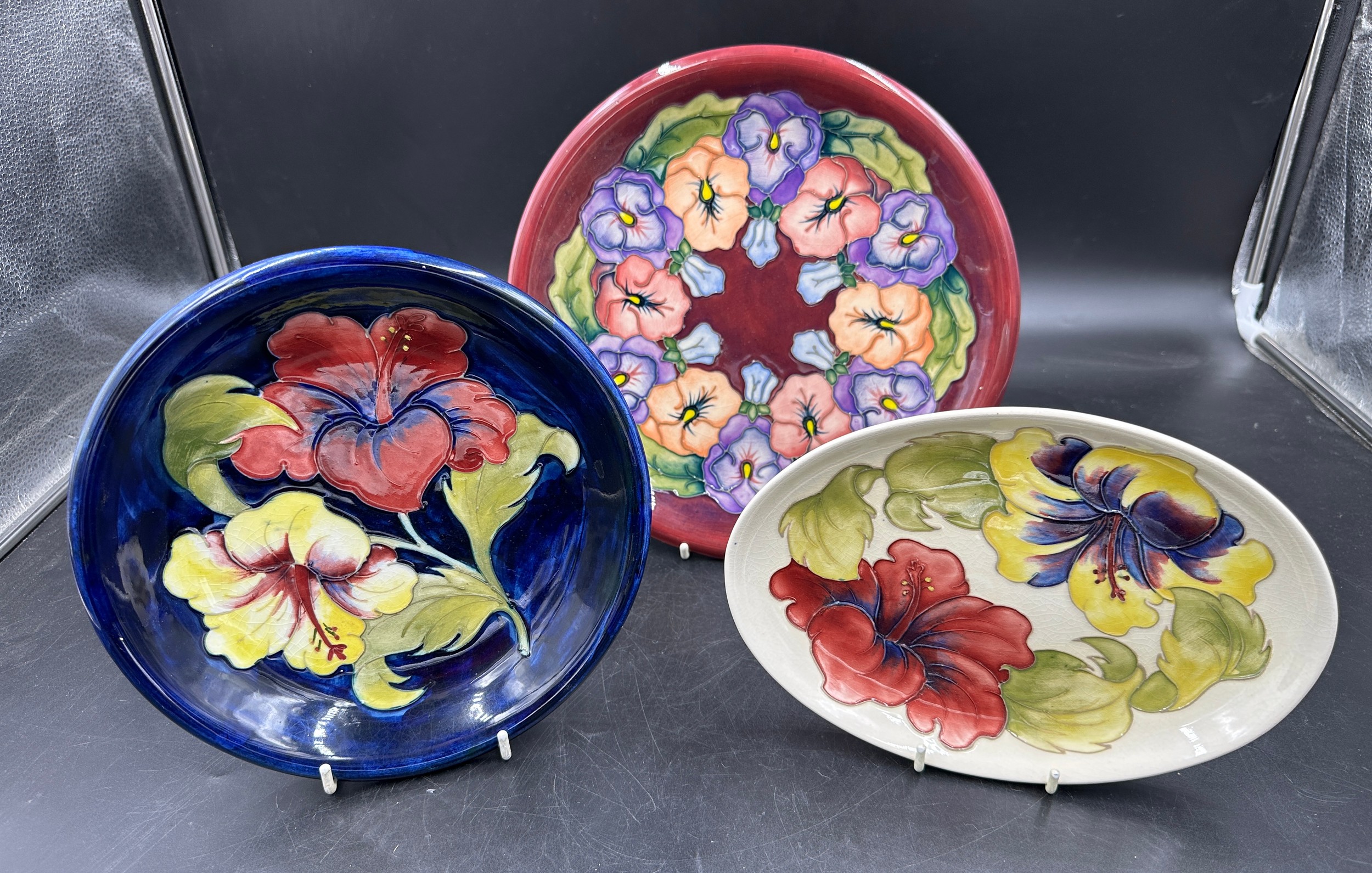 A collection of three Moorcroft plates largest 26cm d in the Pansy pattern, two in the Hibiscus