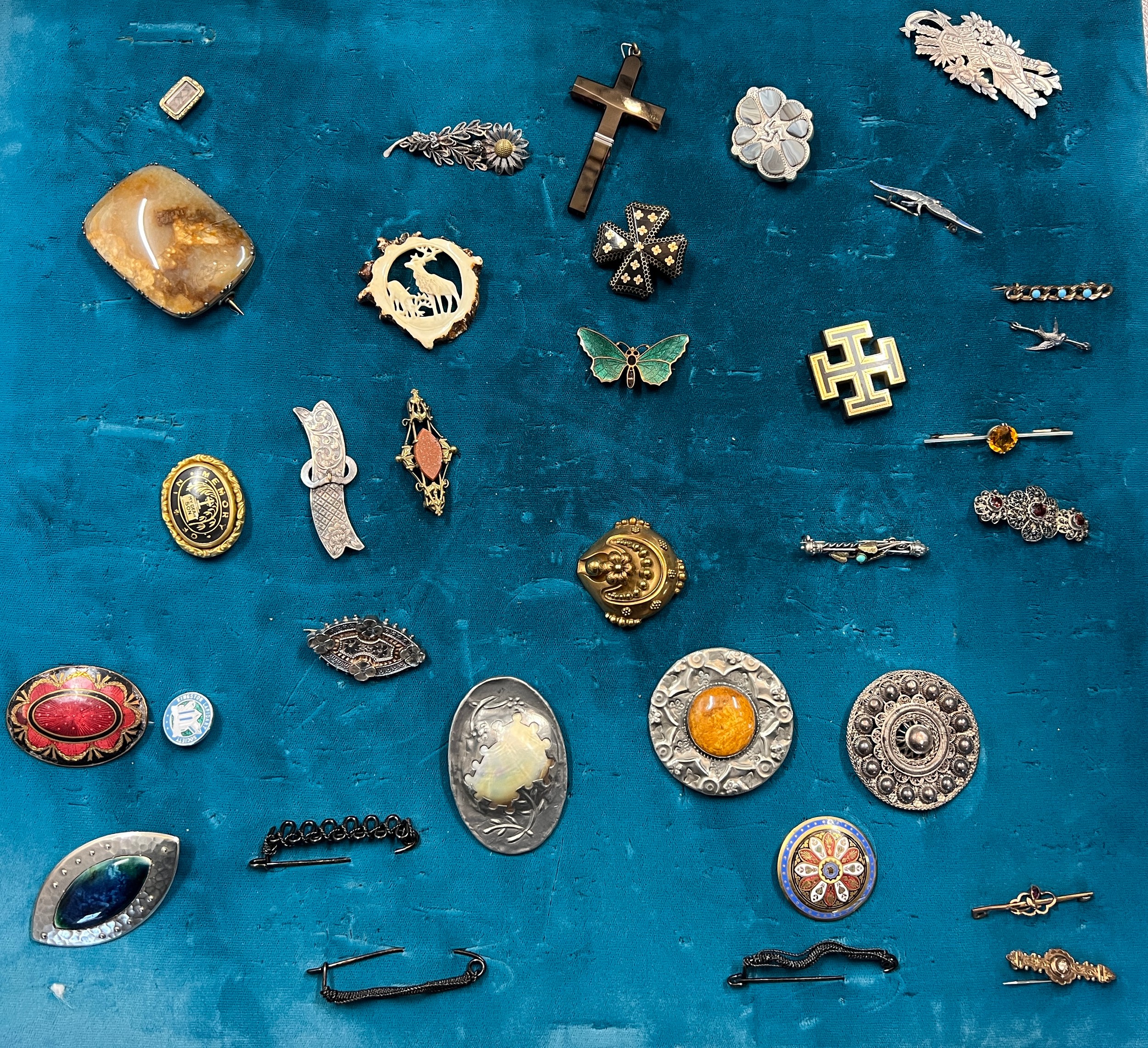 A blue velvet covered board with a collection of 19th and 20thC brooches to include silver, banded