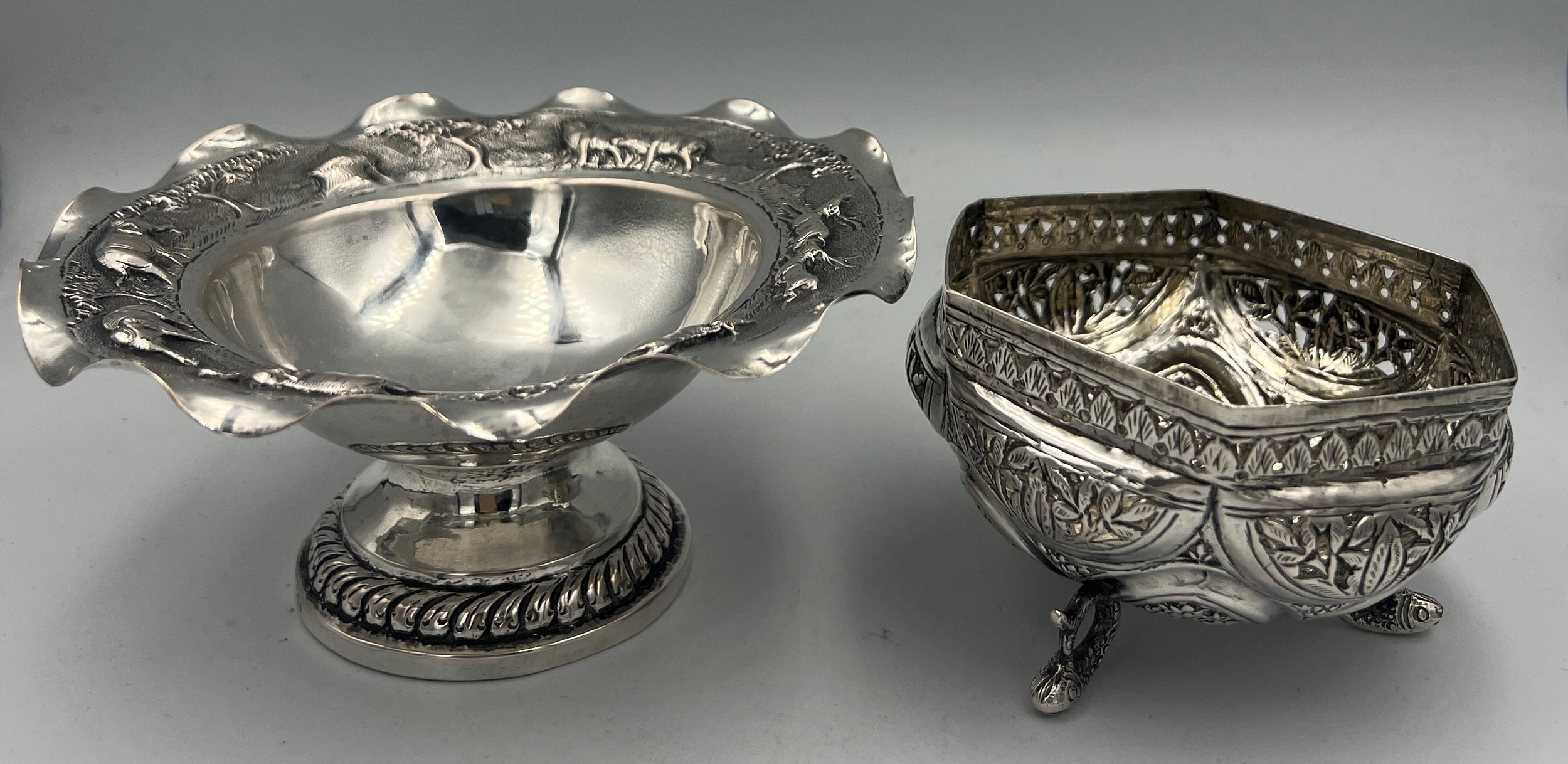 Two Indian white metal bowls, one on a pedestal and embossed with elephants and other animals, the
