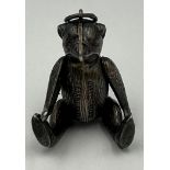 A silver pin cushion in the form of an articulated teddy. 4.5cm h. Birmingham 1909, maker HV