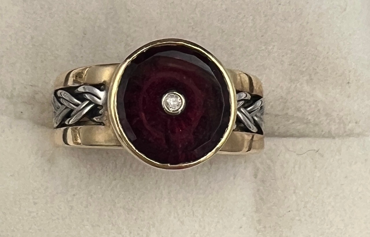 A 9 carat gold ring set with garnet and diamond. Size N. Weight 4.5gm. With certificate of