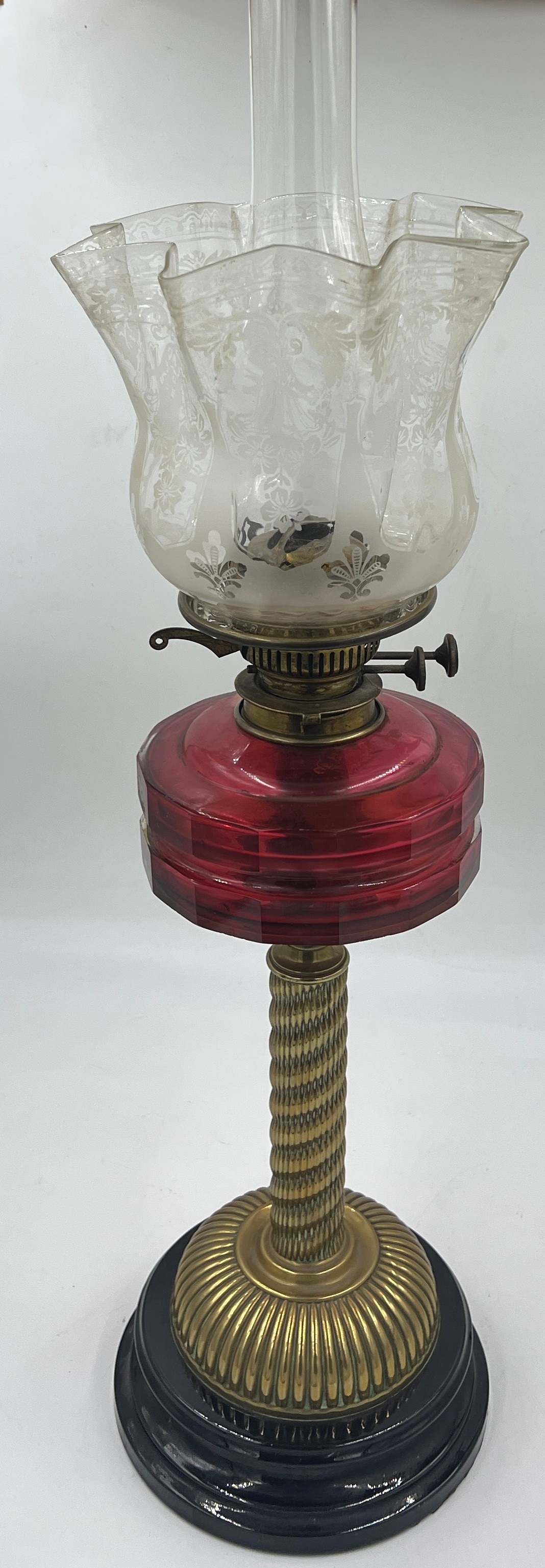 A 19thC cranberry glass and brass oil lamp on black ceramic base with etched glass shade and clear