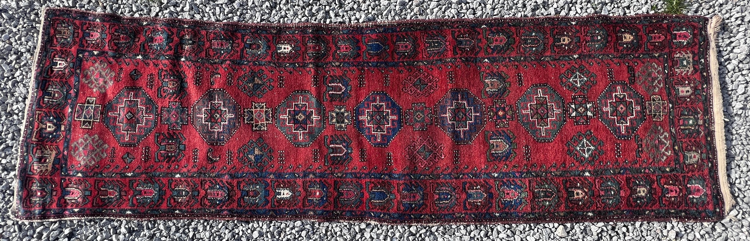 A red ground wool carpet runner 273 x 80cm.