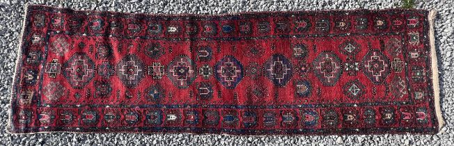 A red ground wool carpet runner 273 x 80cm.