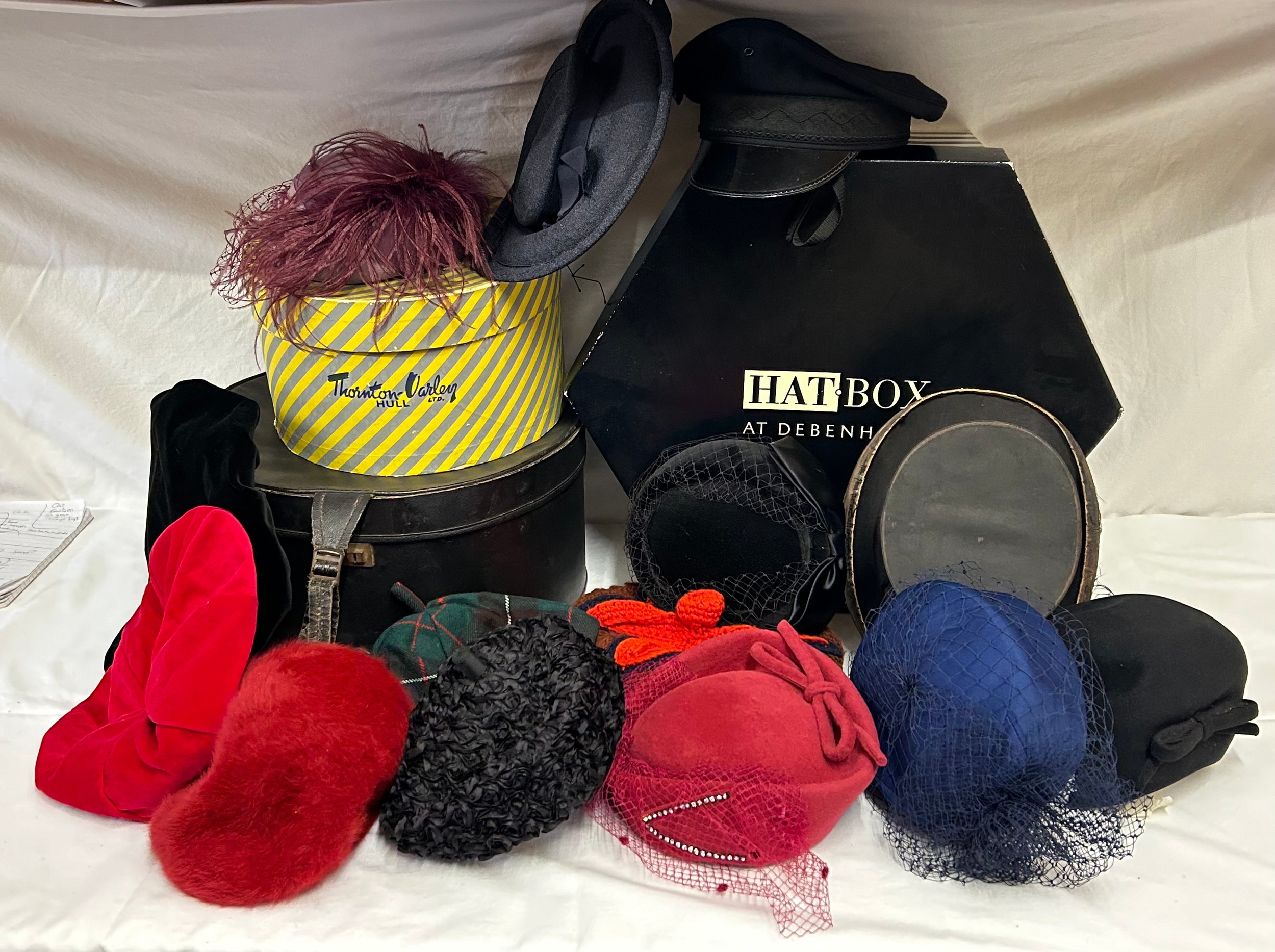 A collection of various hats to include a collapsible opera top hat, a silk pleated lilac hat with