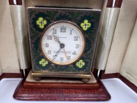 An early 20th century brass cloisonné cased Zenith travel alarm clock in good quality fitted leather