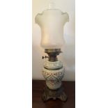 A 19thC ceramic and cast iron oil lamp with glass shade. 48cm h.