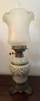 A 19thC ceramic and cast iron oil lamp with glass shade. 48cm h.