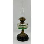 A vintage brass paraffin lamp with black ceramic base complete with glass chimney. 56cm h.