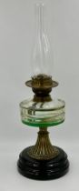 A vintage brass paraffin lamp with black ceramic base complete with glass chimney. 56cm h.