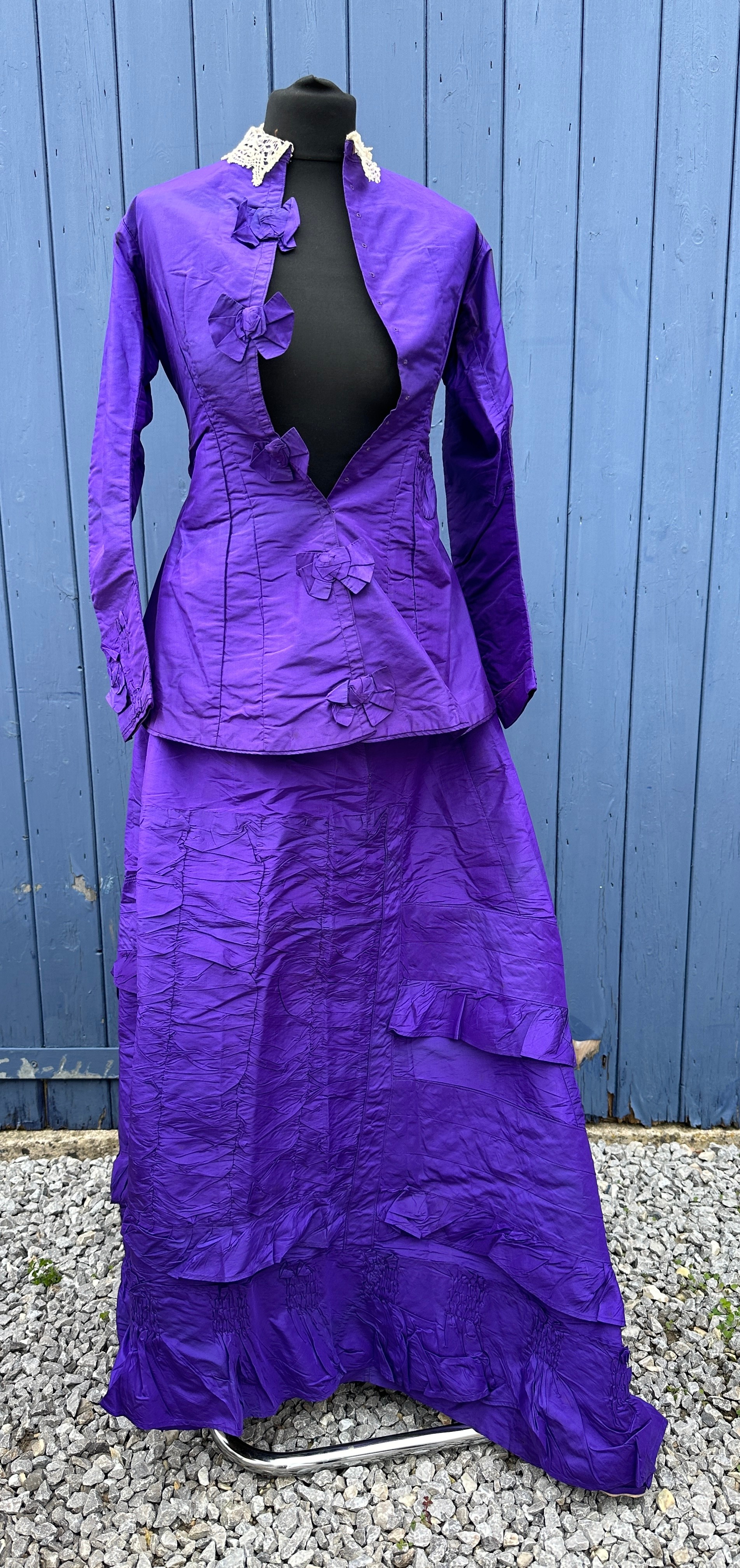A Victorian taffeta purple skirt and bodice with hooks and bows to the front and lace collar.