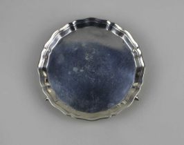 A George V small circular silver card tray with pie crust border on three cast scroll feet, maker