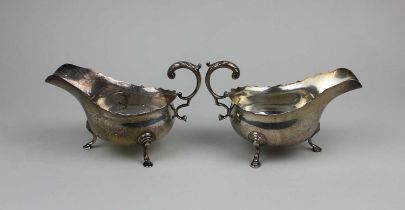 A pair of George V silver sauce boats with flying scroll handles on three hoofed feet, maker