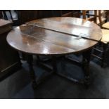 An antique oak drop leaf table single semi circular leaf forming circular four plank top, with metal