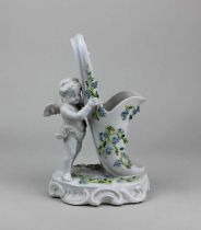 A Sitzendorf porcelain vase in the form of a cherub supporting a shoe decorated with forget-me-