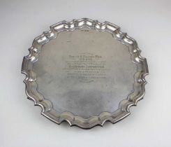 A George V silver salver, presentation engraved within a piecrust border on three scroll feet, 31.