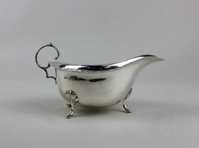 A George VI silver sauce boat, with flying scroll handle, on three hoof feet, maker Mappin & Webb,