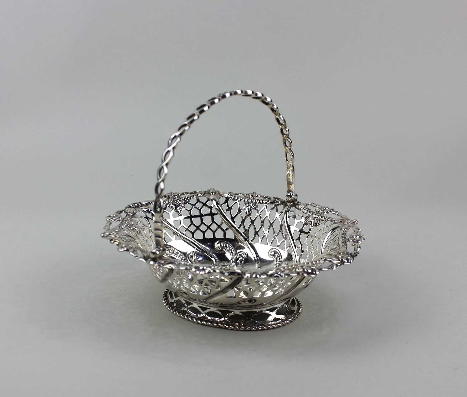 A small silver basket with swing handle and pierced floral decoration, indistinctly marked, approx