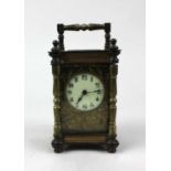 A brass carriage clock with white enamel dial, arabic numerals with floral scroll face, ht 15cm