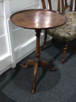 A George III mahogany circular side table with tilting dished top, on baluster stem and tripod base,