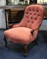 A Victorian button upholstered armchair with walnut frame on scroll feet and castors