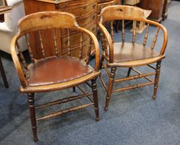 A pair of early 20th century oak elbow chairs with pierced handle back rails on spindle supports