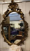 A giltwood oval wall mirror with scroll surmount and pierced border with flowers and cherubs, ht.