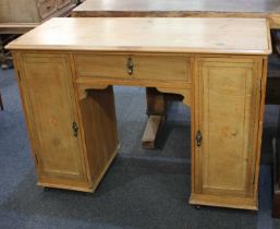 A pine desk with centre drawer flanked by cupboards with brass pear drop handles, 110cm