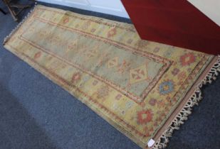 A Turkish wool runner rug pale green rectangular panel with yellow floral border, with