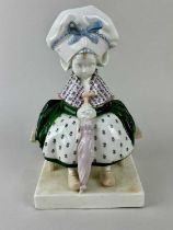 A rare Goldscheider ceramic figure of a Dutch girl in a bonnet sitting on a bench, holding an