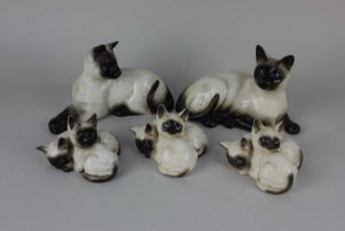 A Beswick porcelain model of a Siamese cat 12cm high and another of two Siamese kittens 8cm high,