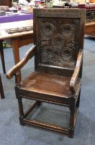 An oak wainscot chair rectangular back with carved roundels, open arms and solid seat, on turned