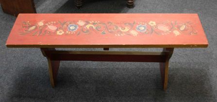 A red and floral painted 'bargeware' bench on shaped supports with uniting stretcher, 119cm