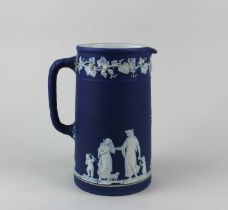 A Wedgwood blue jasper ware jug decorated with classical figures and a border of fruiting vines 19cm