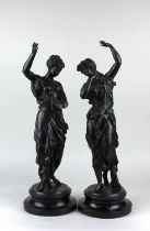 A pair of 19th century spelter classical figures with raised arms, one holding a scroll of music,