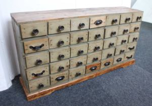 A painted pine cabinet of small drawers five rows of seven drawers on plinth base, 100cm