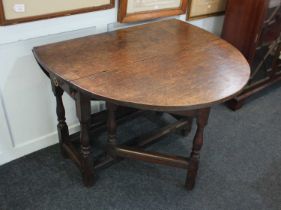 An oak drop leaf gateleg table with oval top on block and turned supports, opens to 116cm