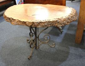 A Burr wood tree trunk side table raised on ornate scrolled wrought iron base. Approx 100cm x 76cm x
