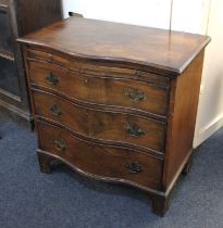 A small mahogany serpentine chest of three drawers with brushing slide and crossbanded top, 74cm