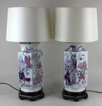 A pair of Japanese ceramic vase table lamps on wooden stands, with figural decoration in blue and